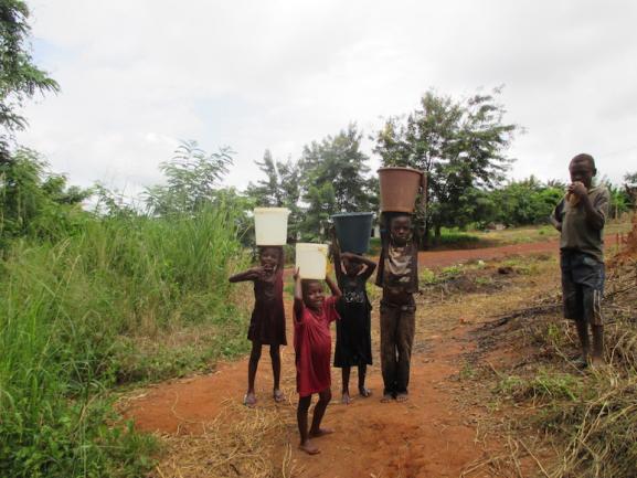 Children carry buckets in rural Ghana.