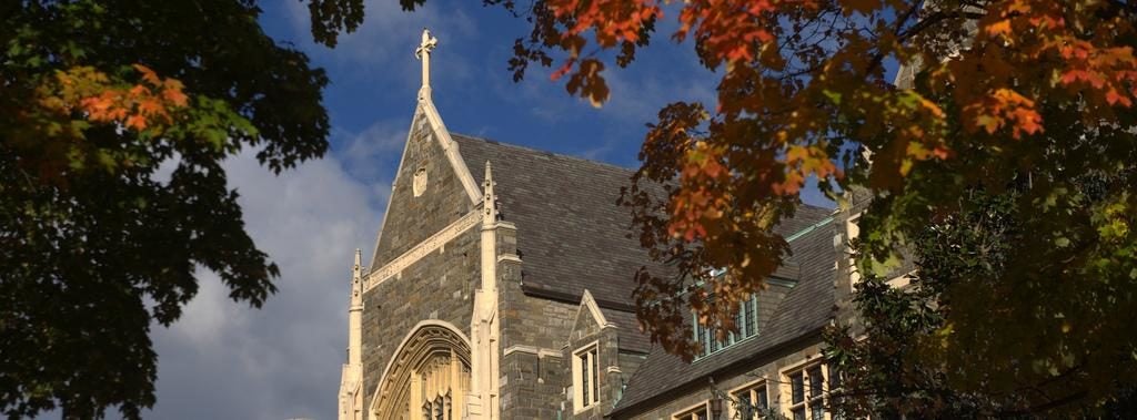 The White Gravenor building on Georgetown's campus with fall foliage in the foreground.