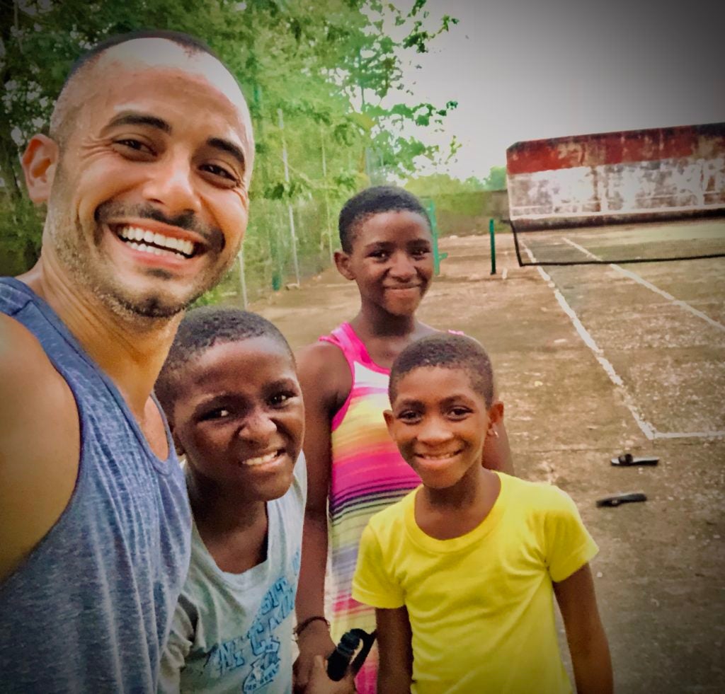 Marco Martinez with children in Navrongo, Ghana on a tennis court.