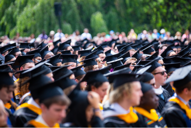 graduates in caps and gowns sitting at Commencement